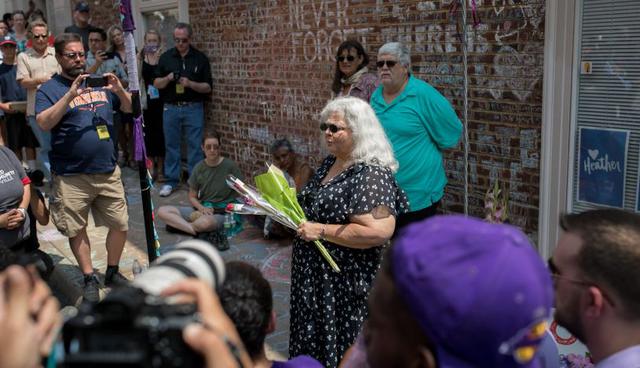 Los deudos se abrazan ante el monumento conmemorativo de Heather Heyer en Charlottesville, Virginia. Fuere resguardo policial en la zona. | Foto: AFP