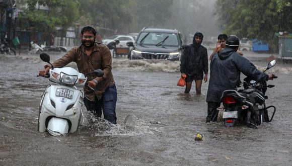 Los motociclistas y automovilistas indios pasan por una calle inundada por las fuertes lluvias tras el paso del ciclón Tauktae en Ahmedabad, India. (EFE / EPA / DIVYAKANT SOLANKI).