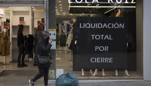 Una mujer pasa junto a una tienda con un letrero que anuncia una venta de liquidación en el centro de Ronda, España, el 22 de enero de 2021, en plena pandemia de coronavirus. (Foto de JORGE GUERRERO / AFP).