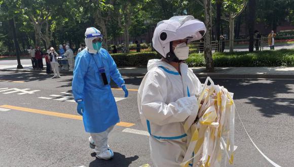 Un trabajador con traje protector retira una línea de cordón de una calle residencial en medio del brote de la enfermedad coronavirus (COVID-19) en Shanghái, China.