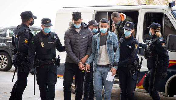 Dos de los migrantes detenidos por entrada ilegal por el aeropuerto de Palma llegan escoltados por policías al juzgado de Palma de Mallorca. (JAIME REINA / AFP).