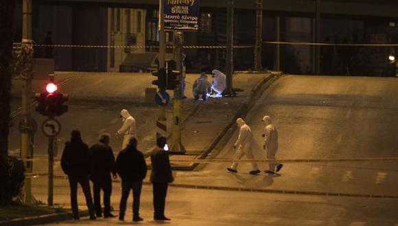 Expertos forenses griegos buscan en la escena después de que una poderosa bomba explotara fuera de la estación de televisión griega privada, en Faliro, Atenas. (Foto: AP)