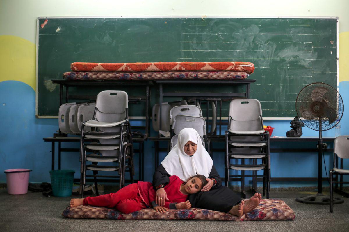 Los ciudadanos palestinos, que huyeron de su hogar debido a los ataques aéreos y de artillería israelíes, descansan en un aula de una escuela administrada por las Naciones Unidas donde se refugian, en la ciudad de Gaza el 15 de mayo de 2021. (REUTERS/Ibraheem Abu Mustafa).