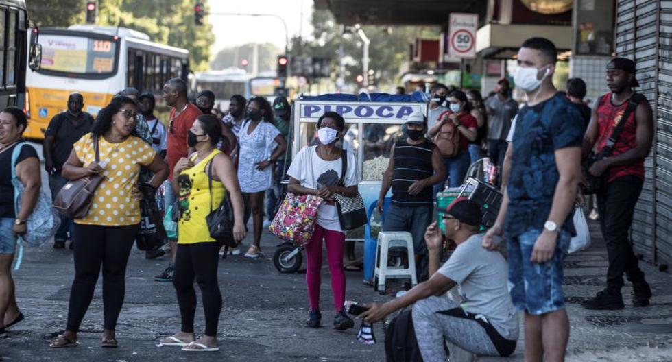 Personas con mascarillas para prevenir la propagación del coronavirus esperan un autobuses en Río de Janeiro (Brasil). (Foto: EFE/Antonio Lacerda).