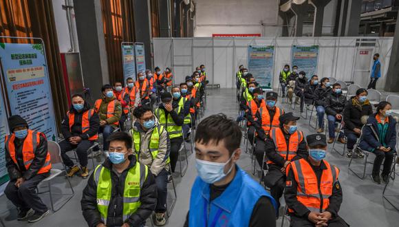 Trabajadores chinos, incluidos los guardias de seguridad, esperan recibir la vacuna contra el coronavirus COVID-19 en un centro de vacunación masiva del distrito de Chaoyang el 15 de enero de 2021. (Foto de Kevin Frayer / Getty Images).