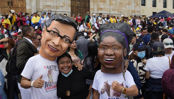 Partidarios del nuevo presidente Gustavo Petro, con máscaras de él y de la nueva vicepresidenta Francia Márquez, a la derecha, esperan la ceremonia de juramentación en la plaza de Bolívar en Bogotá, Colombia.