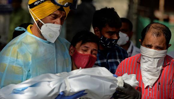 Un hombre llora mientras voluntarios se preparan para realizar los últimos ritos de un niño que murió de coronavirus Covid-19 en Nueva Delhi, India. (Arun SANKAR / AFP).