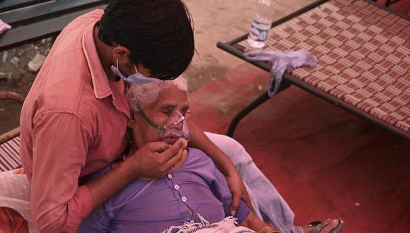 Un familiar consuela a una paciente que respira con la ayuda del oxígeno proporcionado por un Gurdwara, un lugar de culto para los sijs, debajo de una carpa instalada a lo largo de la carretera en medio de la pandemia del coronavirus en la India. (Foto de Tauseef). MUSTAFA / AFP).