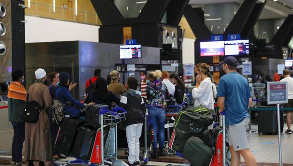 Los viajeros hacen cola en un mostrador de facturación en el Aeropuerto Internacional OR Tambo en Johannesburgo el 27 de noviembre de 2021, después de que varios países prohibieran los vuelos desde Sudáfrica tras el descubrimiento de la variante Ómicron del coronavirus. (PHILL MAGAKOE / AFP).