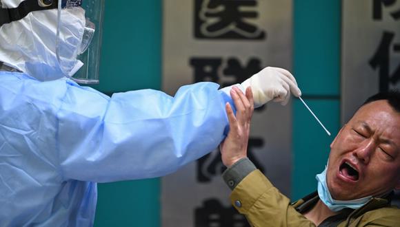 Un hombre al que se le hace la prueba del nuevo coronavirus COVID-19 reacciona cuando un trabajador médico le toma una muestra en Wuhan, China, el 16 de abril de 2020. (Foto de Hector RETAMAL / AFP).