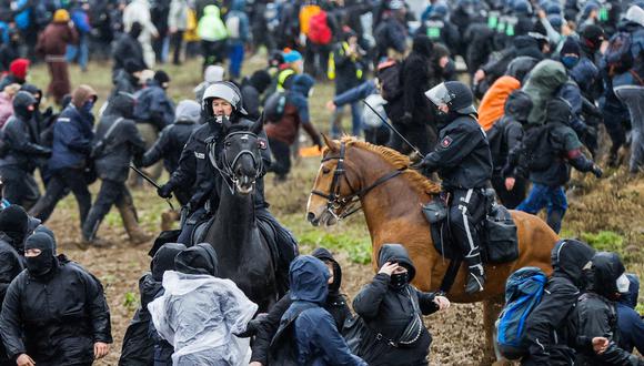 Policías montan a caballo entre los manifestantes durante una manifestación de activistas de protección del clima cerca de la aldea de Luetzerath, Alemania.