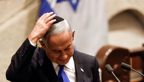 El primer nuevo ministro de Israel, Benjamin Netanyahu, se ajusta la gorra después de hablar en una sesión especial del parlamento para aprobar y jurar el cargo. (AMIR COHEN / AFP).