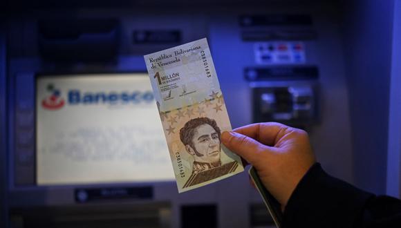 Una persona muestra un billete de un millón de bolívares que seguirá circulando pero con un valor de un bolívar mientras Venezuela devela nuevos billetes para volver a recortar 6 ceros de su moneda. (YURI CORTEZ / AFP).