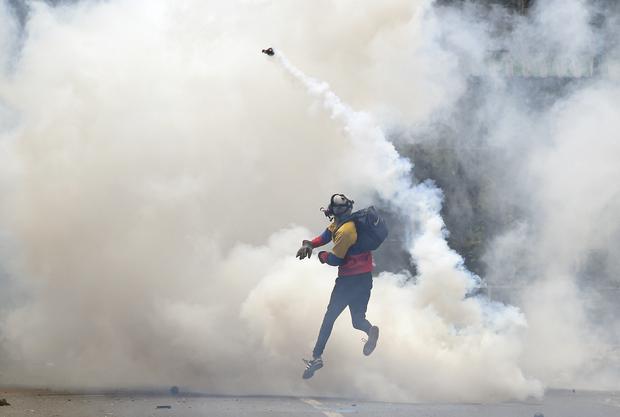 Un activista de la oposición devuelve gases lacrimógenos a la policía, mientras estallan enfrentamientos durante una protesta contra el presidente Nicolás Maduro, el 8 de mayo de 2017. (Foto de JUAN BARRETO/AFP).