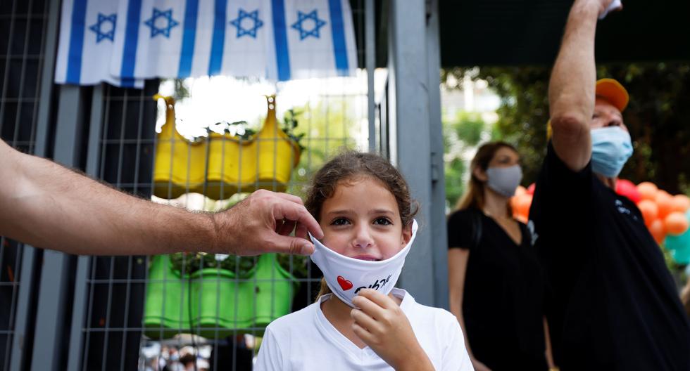 Un padre ajusta una máscara facial en una niña mientras los estudiantes regresan a la escuela después de las vacaciones de verano en la Escuela Primaria Arazim en Tel Aviv. Israel experimenta un repunte de casos de coronavirus COVID-19. (Foto: Reuters)