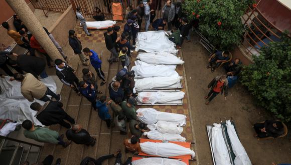 Los palestinos lamentan la muerte de sus seres queridos tras el bombardeo israelí en el sur de la Franja de Gaza el 5 de diciembre de 2023, mientras varios cuerpos yacen afuera de un hospital en Khan Yunis, en medio de continuas batallas entre Israel y el grupo militante Hamas. (Foto de Mahmud HAMS / AFP)