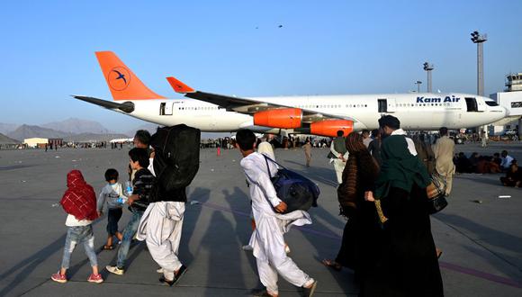 Familias afganas caminan junto a los aviones en el aeropuerto de Kabul el 16 de agosto de 2021, después de un final asombrosamente rápido de la guerra de 20 años de Afganistán. (Wakil Kohsar / AFP).
