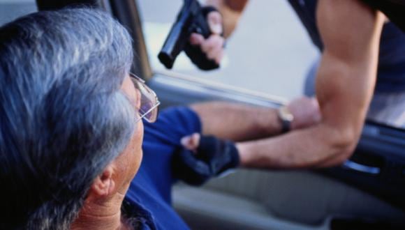 Man with gun threatening motorist through car window,close-up