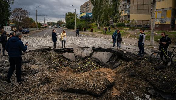 Los residentes locales examinan un cráter luego de un ataque con misiles en Dnipro el 10 de octubre de 2022, en medio de la invasión rusa de Ucrania. (Foto de Dimitar DILKOFF / AFP)