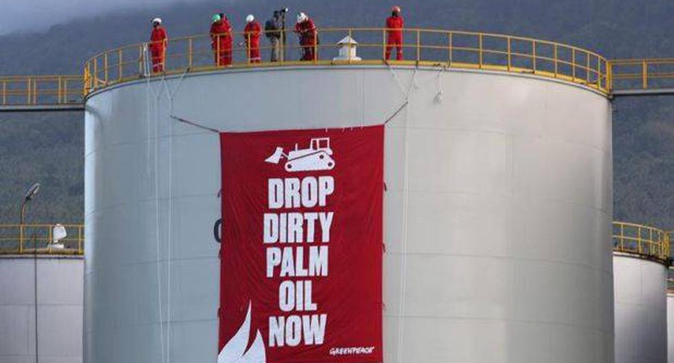 "Abandona el aceite de palma sucio ahora mismo", reza una de las pancartas que los activistas colgaron en los depósitos de la plataforma industrial. (Foto: EFE)