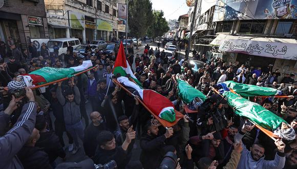 Dolientes cargan los cuerpos envueltos en banderas de los palestinos asesinados durante un ataque israelí en Jenin, en la Cisjordania ocupada, durante su funeral el 7 de enero de 2024. (Foto de Zain JAAFAR / AFP)