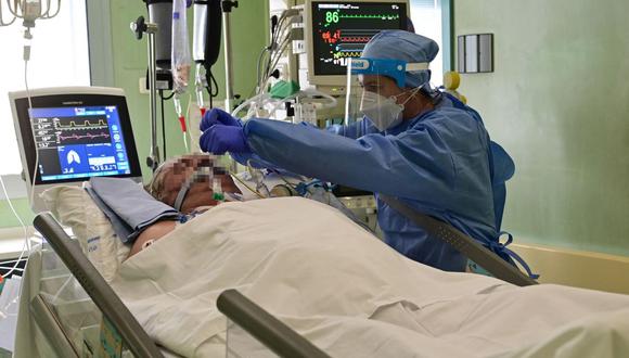 Un miembro del personal médico (izquierda) con equipo de protección personal (EPP) trabaja con un paciente en la unidad de cuidados intensivos (UCI) COVID-19 del hospital Bolognini en Seriate, Bérgamo, el 12 de marzo de 2021. (Miguel MEDINA / AFP).