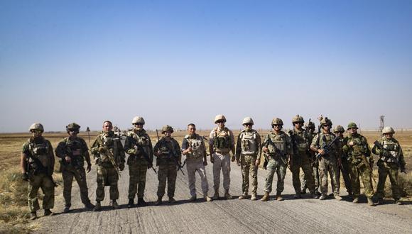 Soldados de un convoy militar ruso y sus homólogos estadounidenses posan para fotografías mientras sus rutas de patrulla se cruzan en un campo petrolero cerca de la ciudad siria de al-Qahtaniyah en la provincia nororiental de Hasakah, cerca de la frontera con Turquía, el 8 de octubre de 2022. (Foto de Delil SOULEIMAN / AFP)