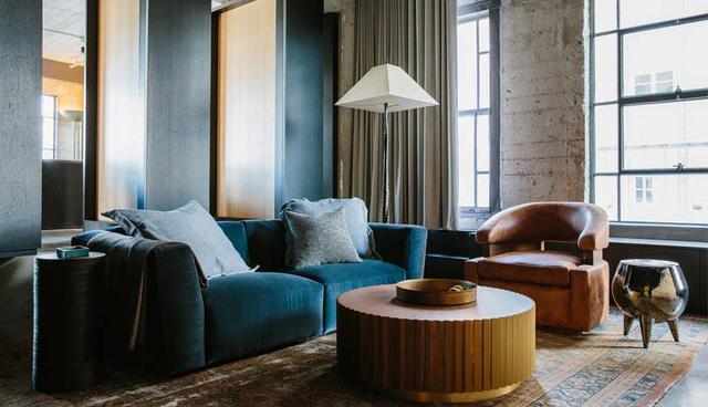 Este loft, además, cuenta con una sala de estar en la que se han incorporado elementos con matices más cálidos, a través de los sofás, los cojines, la alfombra y la mesa de centro. (Foto: Marmol Radziner/ Jessie Webster)