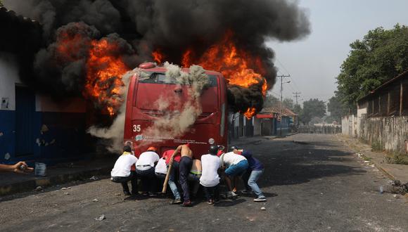 Manifestantes se enfrentan con miembros de la Policía Nacional Bolivariana, junto a un camión que transportaba ayuda humanitaria y que fue quemado. (Foto: AP)