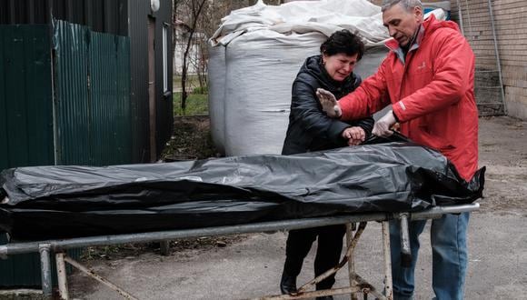 Una mujer y su esposo ven el cuerpo de su hijo, quien fue asesinado a tiros en Myrotske a unos 5 km de Bucha. (Yasuyoshi CHIBA / AFP)