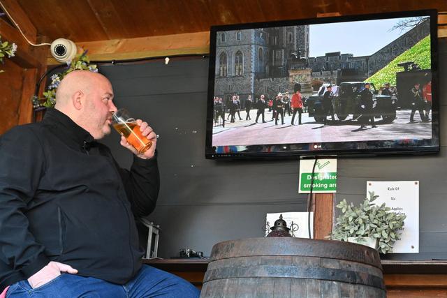 Un hombre bebe alcohol viendo una transmisión en vivo desde Windsor del funeral del príncipe Felipe de Gran Bretaña, duque de Edimburgo en el pub "The Duke of Edinburgh", en Winkfield, al oeste de Londres, el 17 de abril de 2021. (Glyn KIRK / AFP).