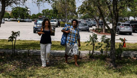 El chef italiano Aldo Giaquinto y su esposa Vera Kozlovskaia caminan para desayunar en un parque cerca de un estacionamiento de Walmart, en Miami. La pareja ha vivido las últimas dos semanas acampando en su Toyota Land Cruiser en el estacionamiento por el coronavirus. (Foto: AFP/Chandan Khanna)