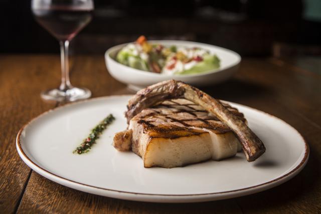 Jugoso corte tomahawk de chuletón de cerdo Duroc. Viene troceado y en su punto.