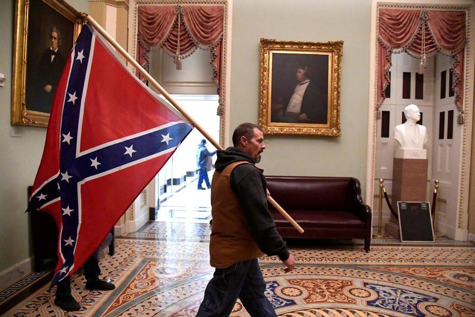 Un partidario del presidente Donald Trump lleva una bandera confederada en el segundo piso del Capitolio de EE. UU. (Foto: Reuters)