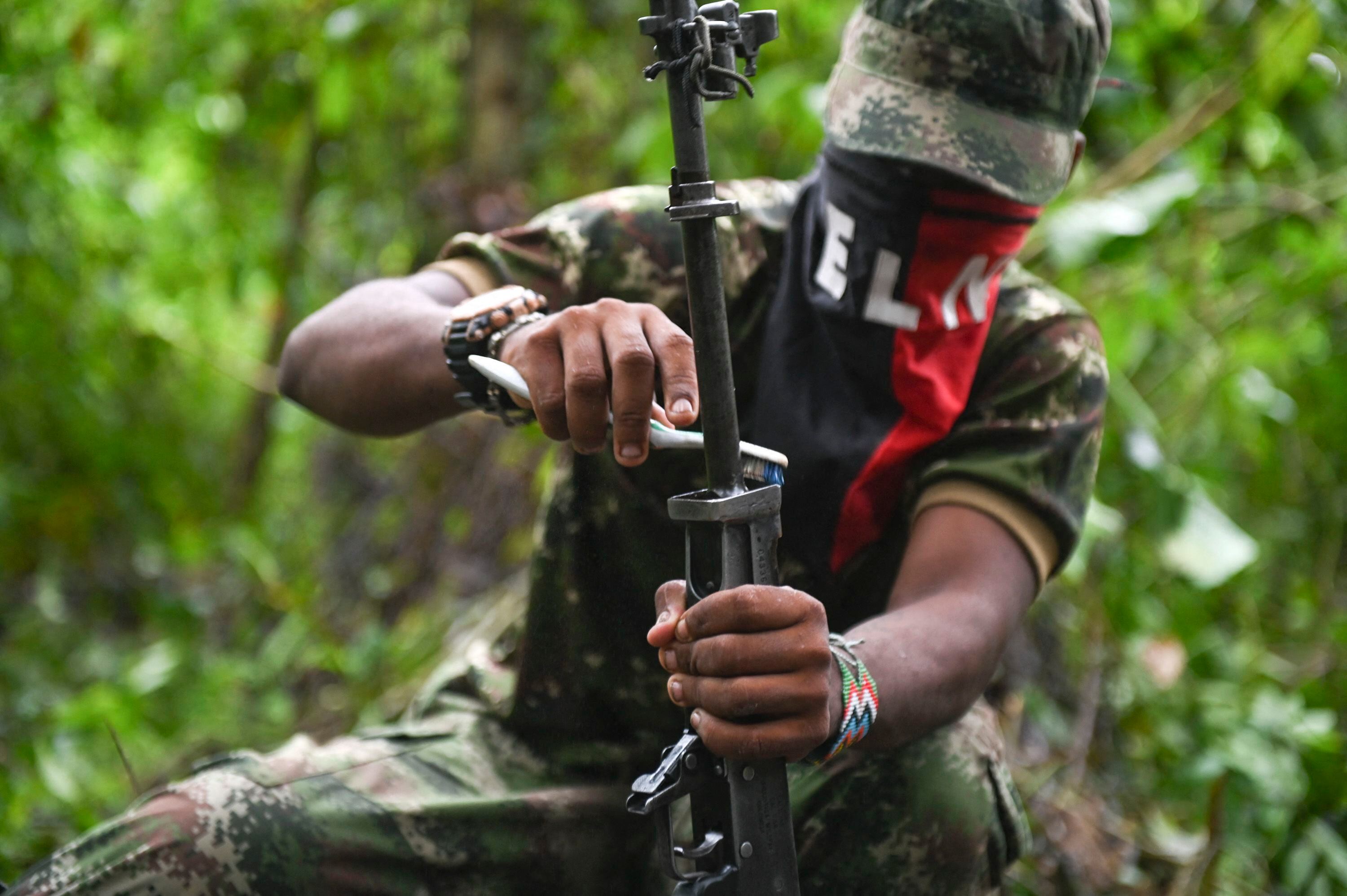 A member of the Ernesto Che Guevara front, belonging to the National Liberation Army (ELN) guerrilla, cleans his weapon in the jungle of Chocó, Colombia, on May 25, 2019. (Photo by Raúl ARBOLEDA / AFP)