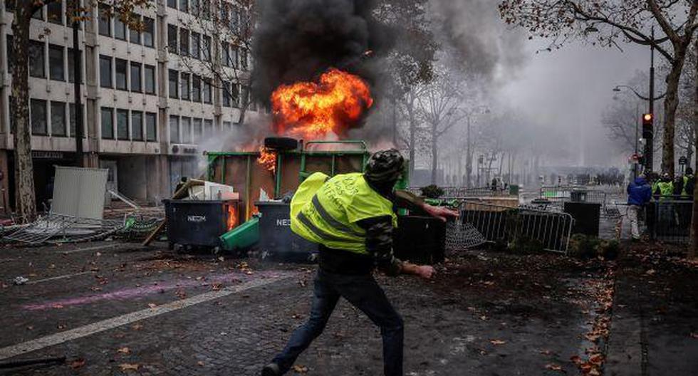 Un manifestante de los autodenominados \"chalecos amarillos\" se enfrenta a los agentes junto a una barricada en llamas durante los disturbios ocurridos en el transcurso de una manifestación. (Foto: EFE)