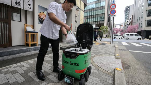 Un empleado de un restaurante coloca un pedido de comida en el pequeño vehículo autónomo, una prueba de Uber Eats de Japón en el centro de Tokio sobre la viabilidad de tener una flota de repartidores robots.
