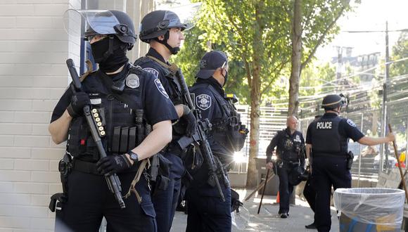 Policías de Seattle con armas hacen guardia frente al edificio del Precinto Este de Seattle, en esta fotografía de archivo del domingo 19 de julio de 2020. Los manifestantes rompieron ventanas del edificio a primera hora de la tarde. (Foto AP/Ted S. Warren).