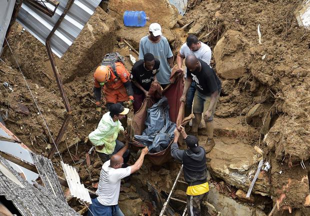 Las personas sacan el cadáver de una persona de entre los escombros después de un deslizamiento de tierra en Petrópolis, Brasil, el 16 de febrero de 2022. (CARL DE SOUZA / AFP).