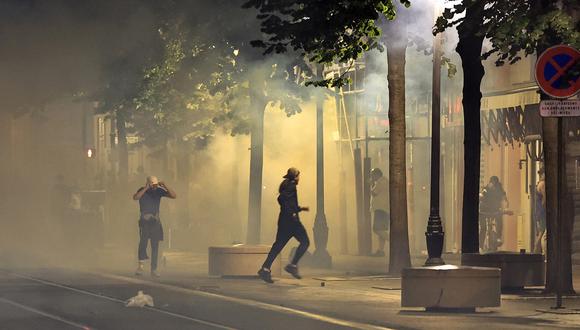 Manifestantes huyen del humo en una calle de Niza, sureste de Francia, a principios del 2 de julio de 2023. (Foto de Valery HACHE / AFP)