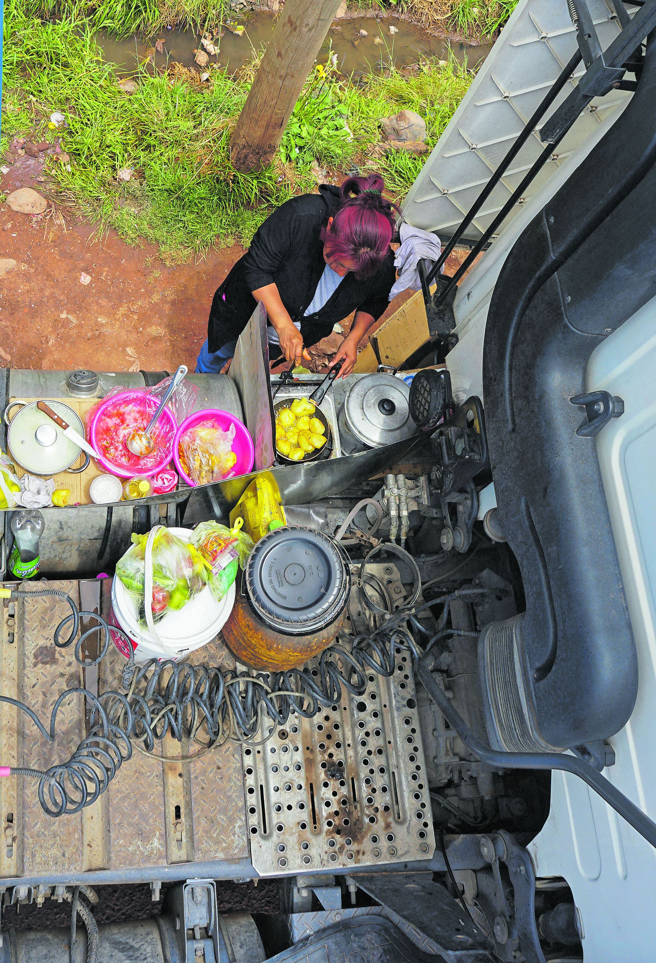 Una mujer prepara una comida en una pequeña cocina improvisada en la estructura de un camión mientras los choferes esperan la apertura de la frontera. (Foto: Bernat BIDEGAIN / AFP)