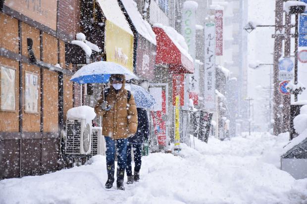 People walk down a street covered in heavy snow in the city of Toyama.