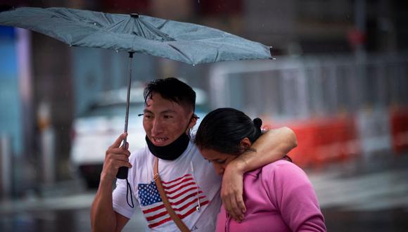 Una pareja cruza la calle mientras la lluvia cae en Times Square antes del impacto de la tormenta tropical Henri en Nueva York. (KENA BETANCUR / AFP).