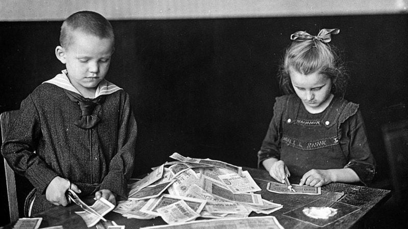 German children destroy banknotes that were no longer valuable with scissors.  (GETTY IMAGES).