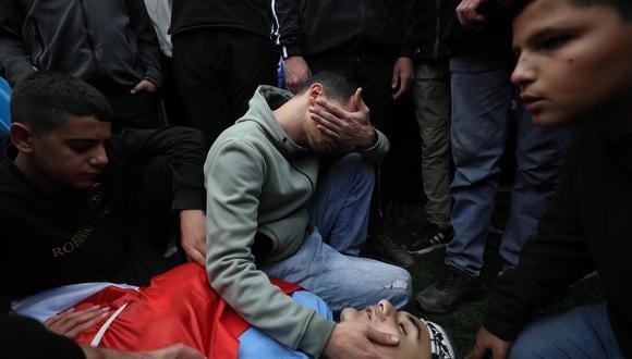 La gente llora junto a un cuerpo durante el funeral de seis palestinos en la ciudad de Tulkarem, en Cisjordania, el 27 de diciembre de 2023, después de una incursión del ejército israelí en el campo de refugiados de Nur Shams. (EFE/EPA/ALAA BADARNEH).