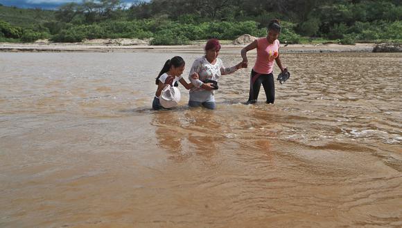 En el distrito de Casitas, Tumbes, personas cruzan las quebradas llenas de agua.