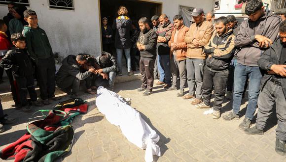 Los palestinos lloran cerca de un cuerpo en el hospital Kamal Edwan en Beit Lahia, en el norte de la Franja de Gaza, el 29 de febrero de 2024, después de que soldados israelíes supuestamente abrieran fuego contra residentes de Gaza que se apresuraron hacia camiones cargados con ayuda humanitaria en medio de batallas en curso entre Israel y el militante grupo Hamás | Foto: AFP