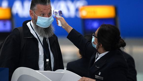 En esta foto de archivo tomada el 10 de julio de 2020, se le toma la temperatura a un pasajero mientras hace cola en un mostrador del aeropuerto de Heathrow, en medio de la pandemia de coronavirus. (Foto de DANIEL LEAL-OLIVAS / AFP).