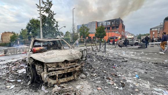 A burnt out vehicle stands on a street in front of the fire damaged Tessi group building in the Alma district of Roubaix on June 30, 2023, which was completely destroyed by fire during protests after a 17-year-old boy was shot in the chest by police at point-blank range in Nanterre, a western suburb of Paris. . The building, which housed a data processing company for banks and insurance companies, completely burned down, following another night of tension after the death of the teenage driver in the Paris suburb of Nanterre on June 27. President Emmanuel Macron left early from an EU summit in Brussels to return to France, where three nights of unrest over the police shooting of a teenager have taken place. (Photo by DENIS CHARLET / AFP)