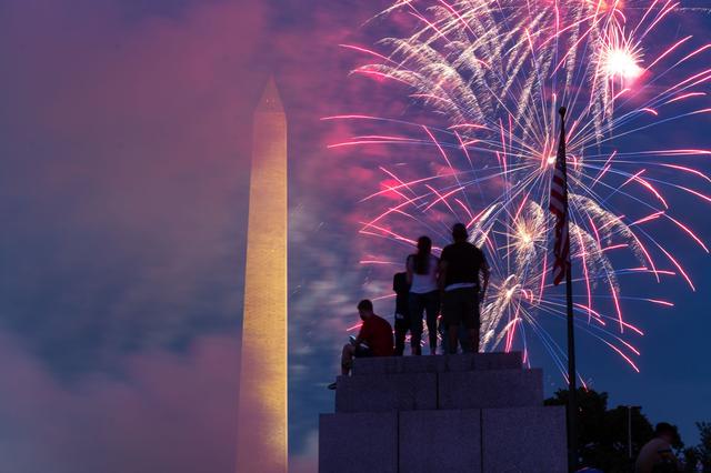 El público se sienta en la cima de un pilar en el Memorial de la Segunda Guerra Mundial mientras los fuegos artificiales estallan en Washington, DC durante las celebraciones por el Día de la Independencia de Estados Unidos. (Foto de ROBERTO SCHMIDT / AFP).
